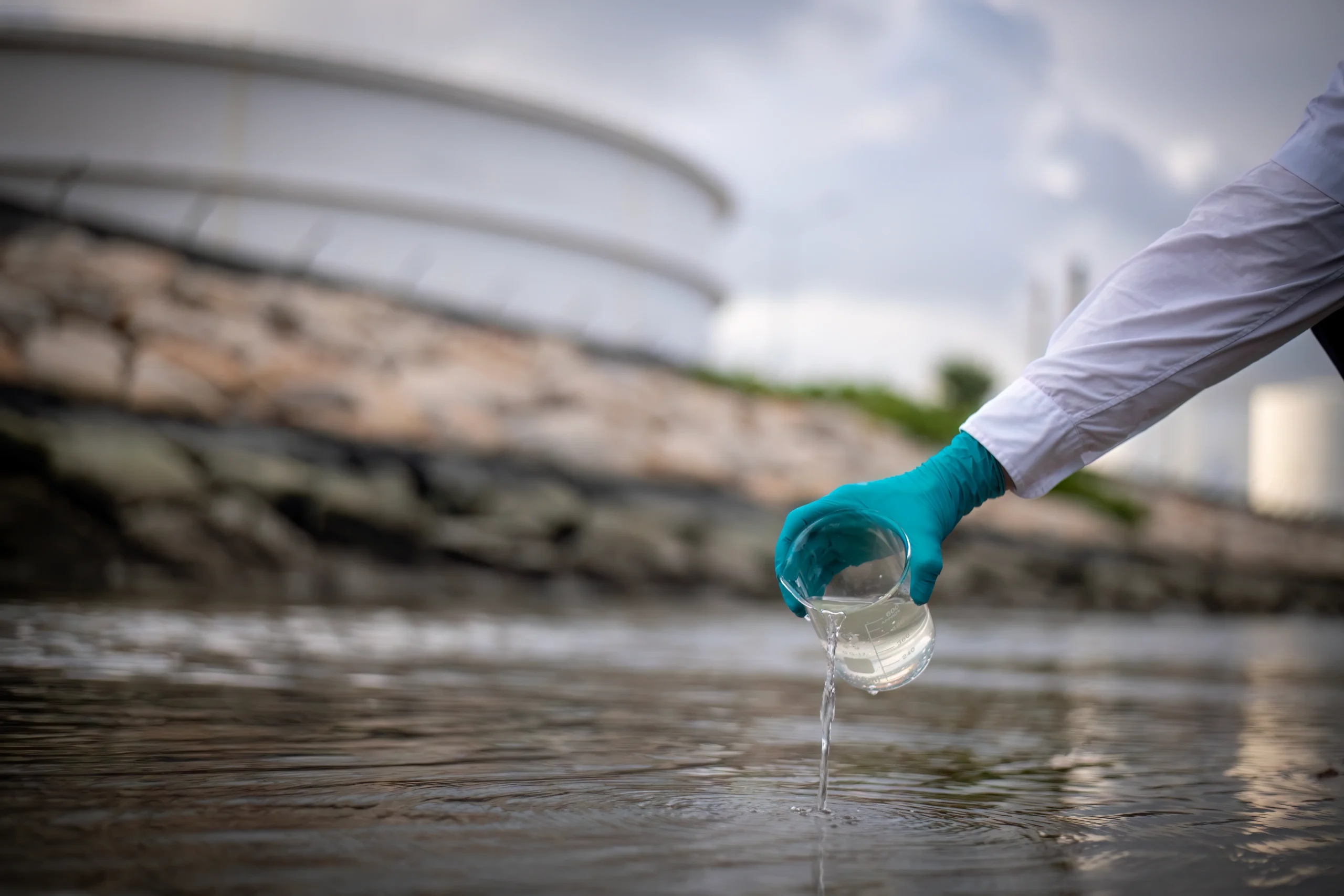 una-persona-esta-sosteniendo-un-vaso-que-tiene-un-guante-azul-en-el toma de muestra del agua de lluvias